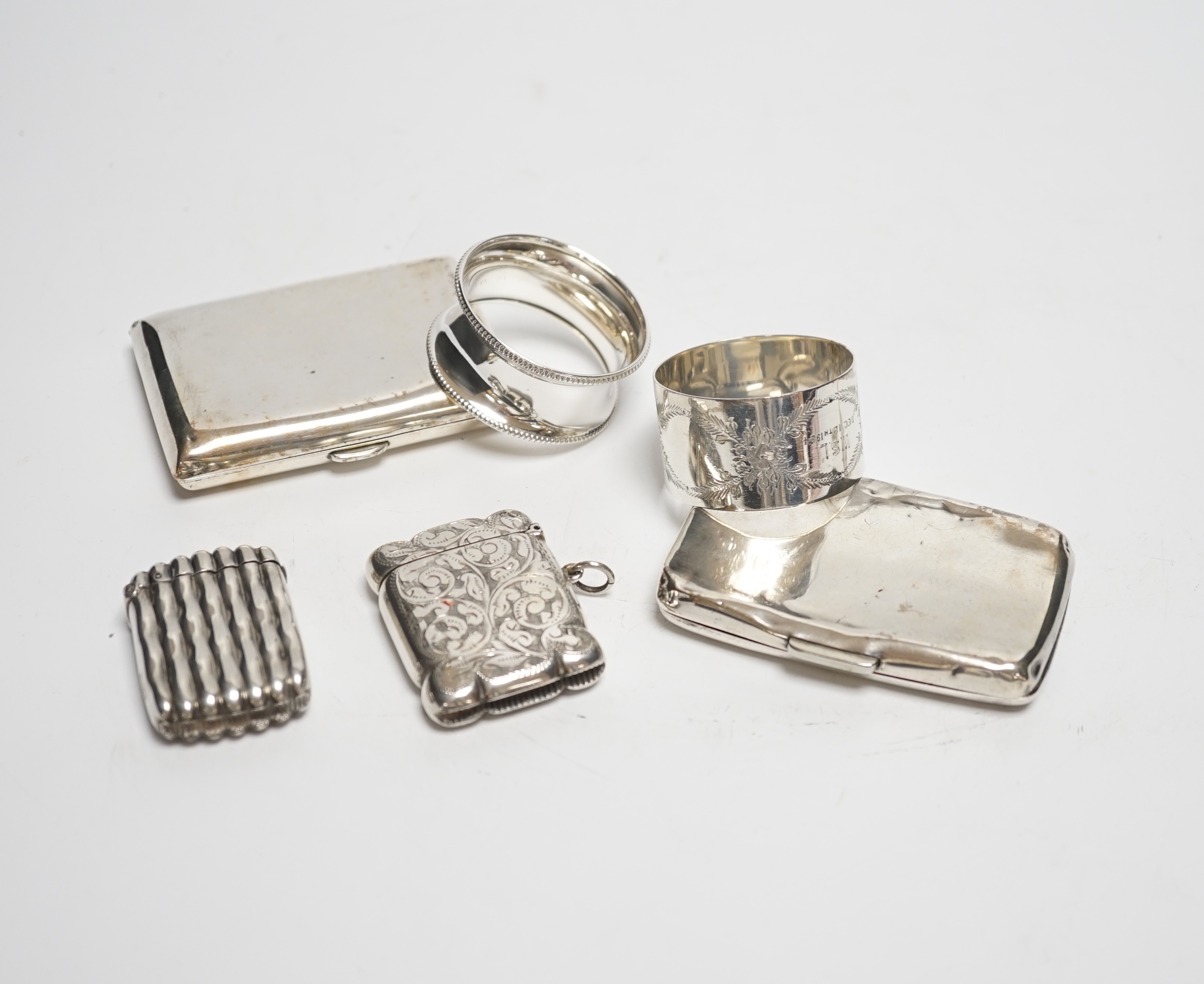 Two silver napkin rings, two silver cigarette cases and two silver vesta cases.